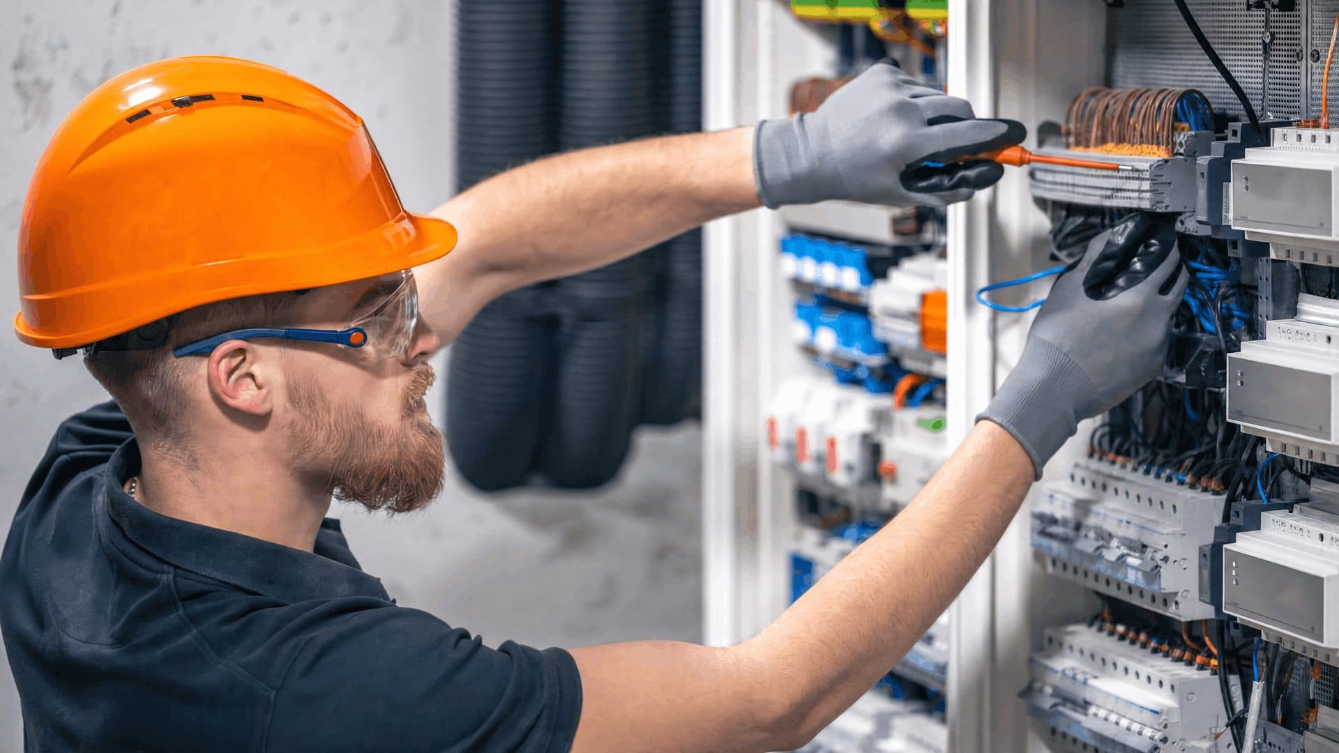 An electrician terminating conductors inside a distribution panel.